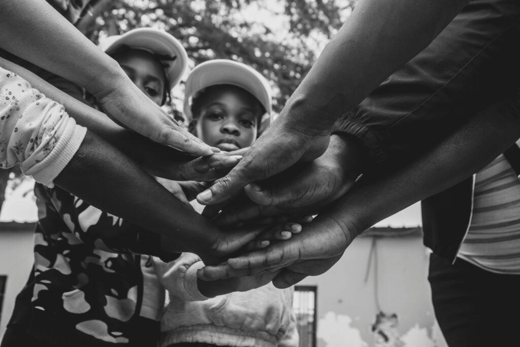 Home A group of diverse hands joined in solidarity, symbolizing unity and community support in Luanda, Angola.